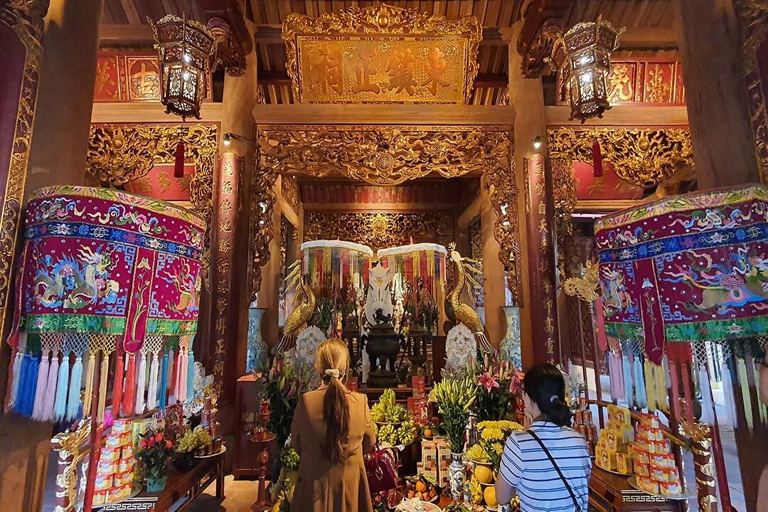 A few people are praying at the Bach Ma Temple