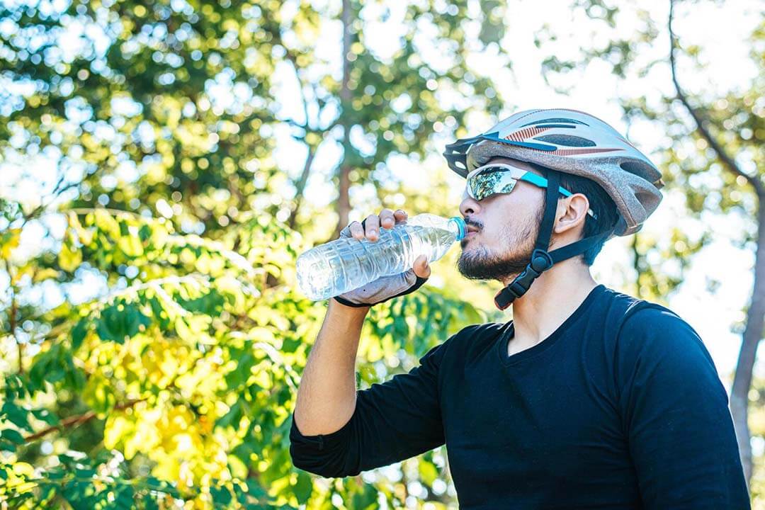 Cyclist stand on the top of the mountain and drink water